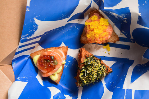 Three small pizzas with different toppings on a blue and white patterned paper.
